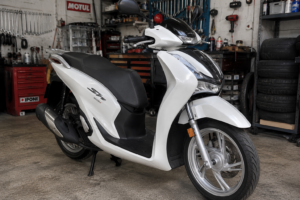Scooter Honda SH125i blanca de 2022 en un garaje junto a herramientas de mecánica, representando la consulta legal sobre despiezar una moto con embargo municipal.